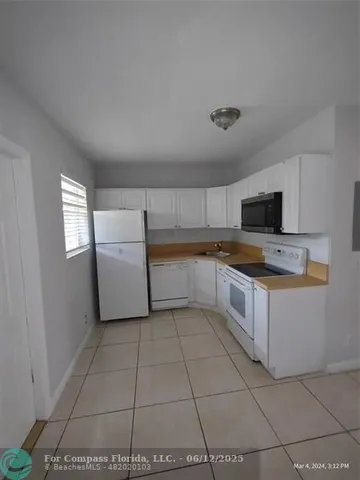 a large white kitchen with a stove a microwave and a refrigerator