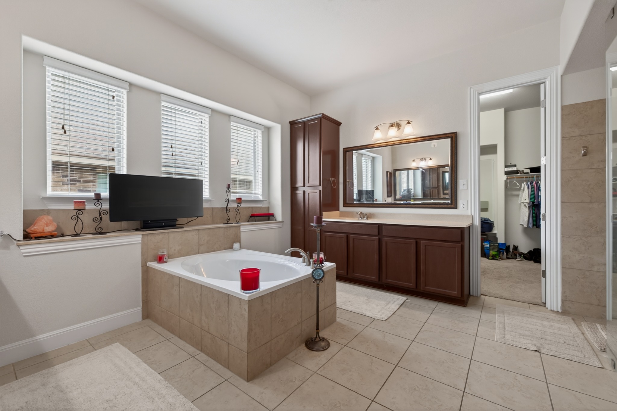 1017 Tabernash Leander, TX 78641 - Photo 22 of 38 Bathroom featuring a built-in tub with tile surround, a dark wood vanity with a light countertop, an integrated mirror with overhead lighting, and tiled flooring