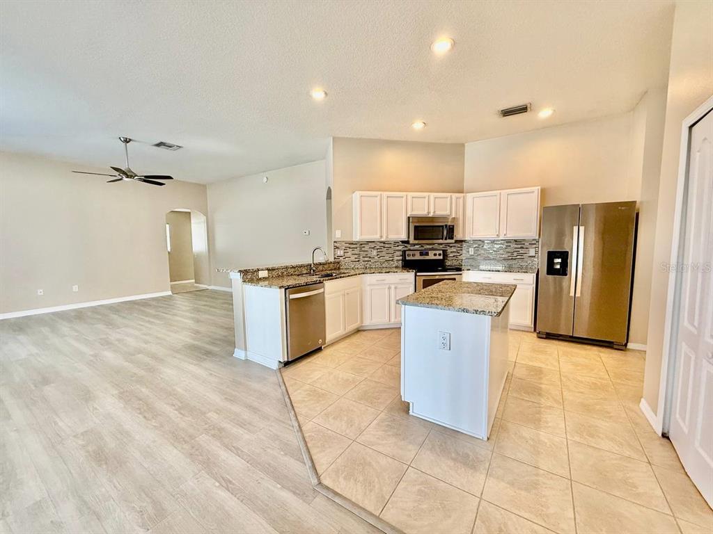 22320 Red Jacket Lane Land O' Lakes, FL 34639 - Photo 13 of 35 a large kitchen with stainless steel appliances granite countertop a stove top oven a sink and white cabinets
