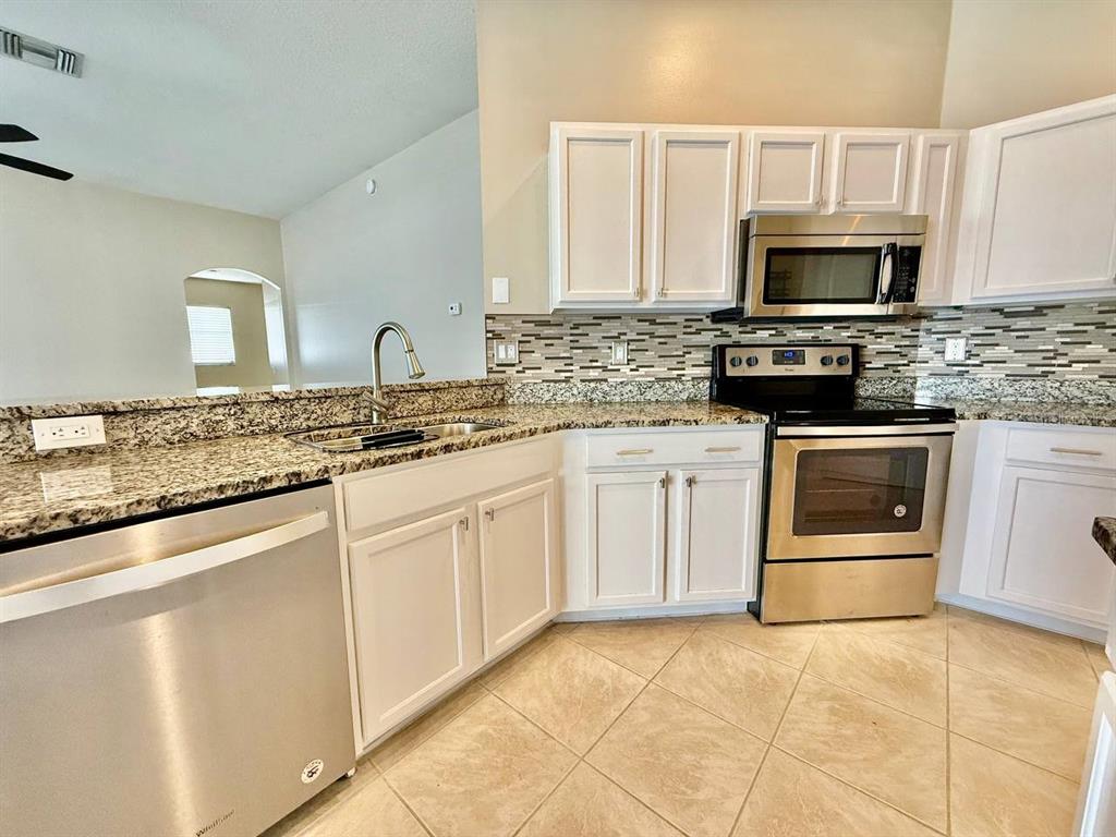 22320 Red Jacket Lane Land O' Lakes, FL 34639 - Photo 14 of 35 a kitchen with granite countertop a stove sink and microwave