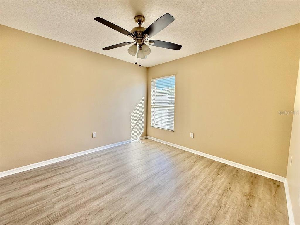 22320 Red Jacket Lane Land O' Lakes, FL 34639 - Photo 25 of 35 an empty room with wooden floor and ceiling fan