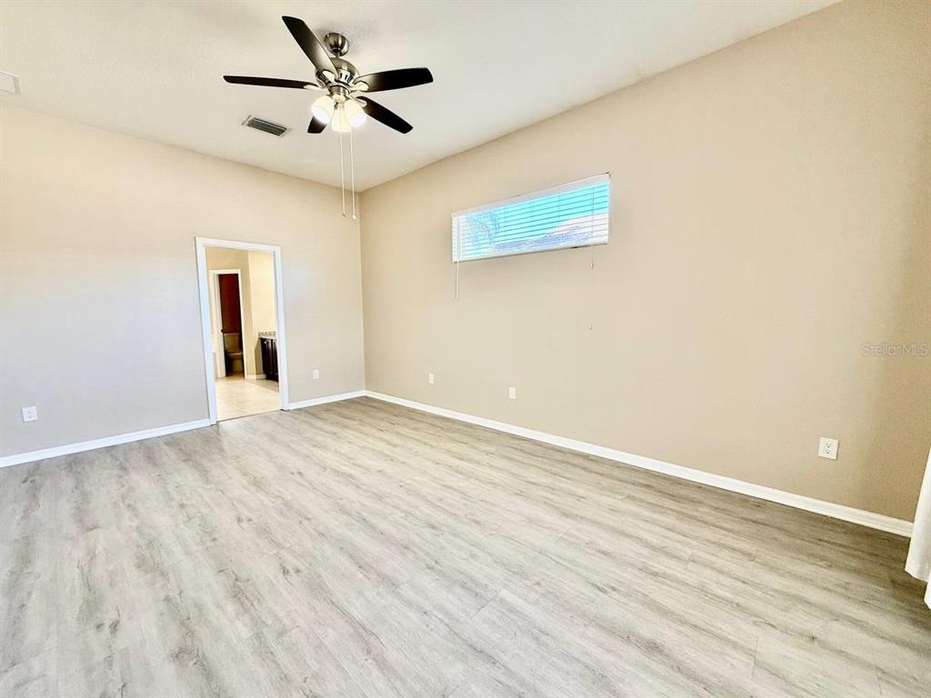 22320 Red Jacket Lane Land O' Lakes, FL 34639 - Photo 8 of 35 an empty room with wooden floor and a ceiling fan