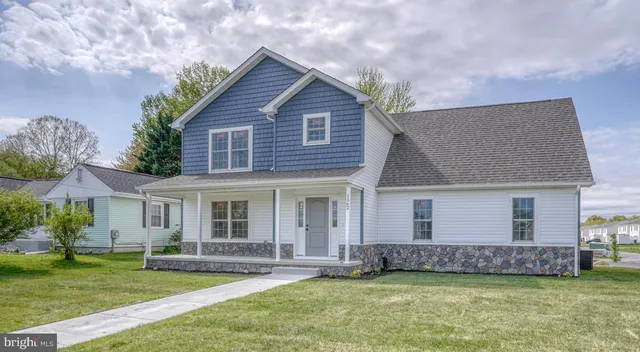 a view of a yard in front of a house with plants and large tree