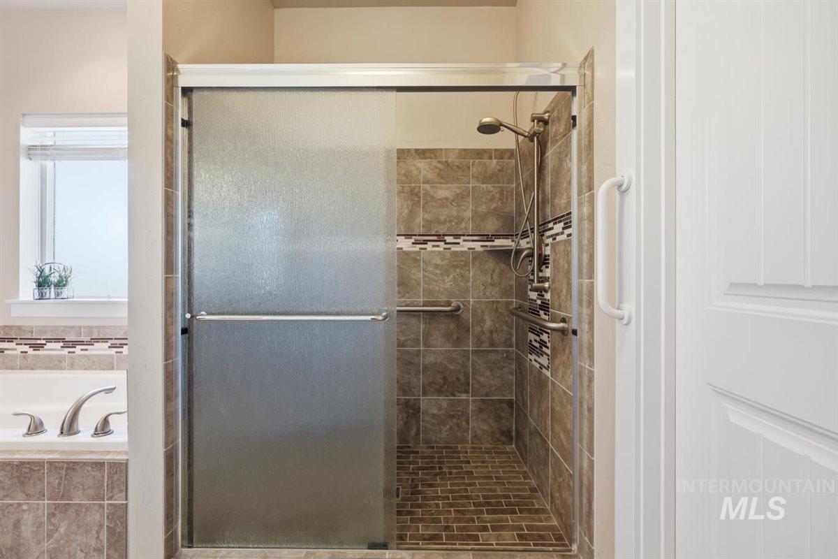 13496 Hockberger Ranch Road Caldwell, ID 83607 - Photo 23 of 40 Walk-in shower featuring sliding frosted glass doors, a mosaic tile accent band, and integrated grab bars