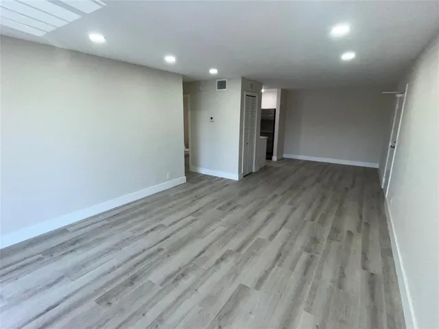 an empty room with wooden floor and natural light