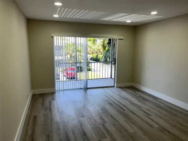 an empty room with wooden floor and fan