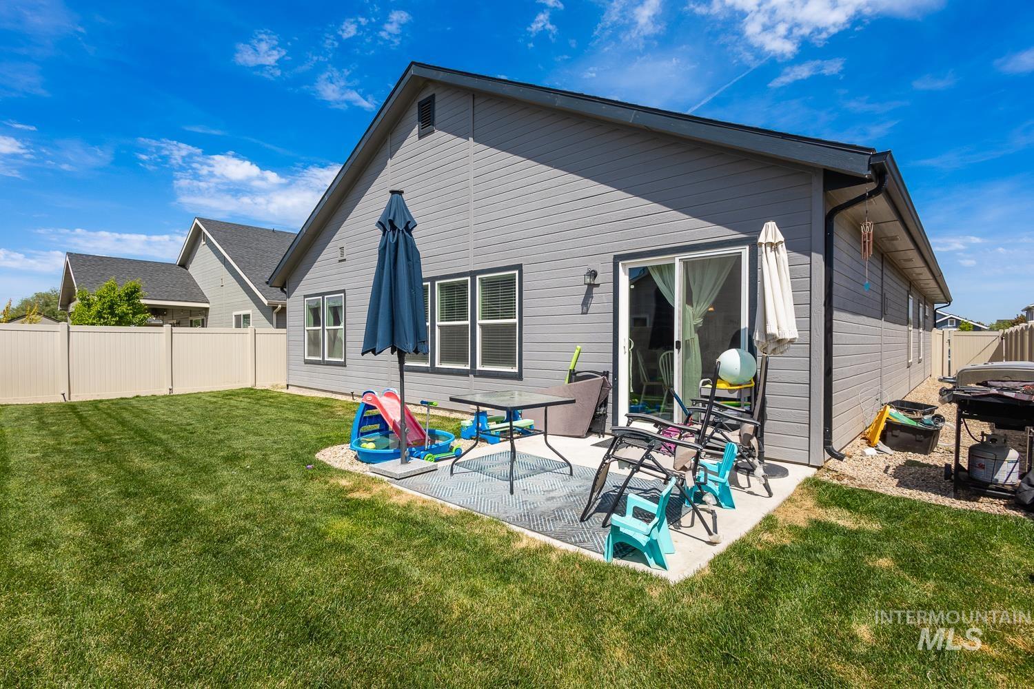 12623 Shadow Peak Street Caldwell, ID 83607 - Photo 47 of 50 Rear exterior featuring gray horizontal siding, a private backyard with a manicured lawn, a concrete patio, and a light-colored vinyl privacy fence