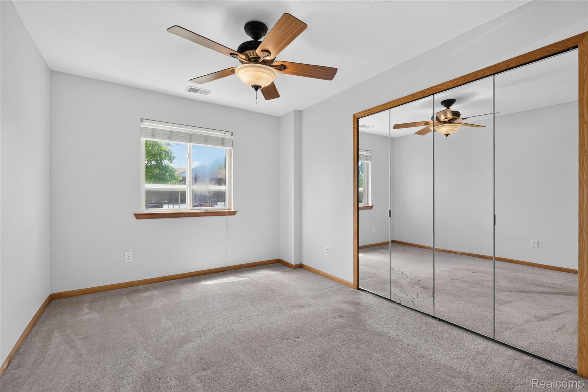 45720 Prairiegrass Court Belleville, MI 48111 - Photo 16 of 31 Carpeted room featuring a ceiling fan with integrated lighting, a window with a wood sill, and a mirrored closet with wood-finish trim
