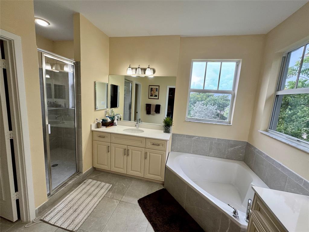 4803 Northwest 48th Terrace Tamarac, FL 33319 - Photo 16 of 28 a bathroom with a tub a double vanity sink and a mirror