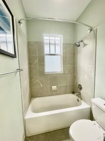 a bathroom with a bathtub a window and a shower