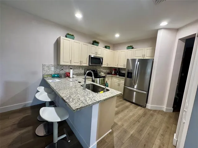 a kitchen with stainless steel appliances granite countertop a sink refrigerator a stove a microwave and a refrigerator