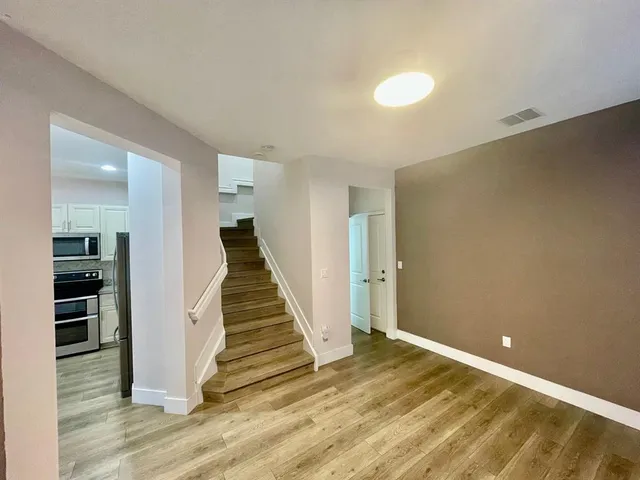 a view of a hallway with wooden floor and staircase