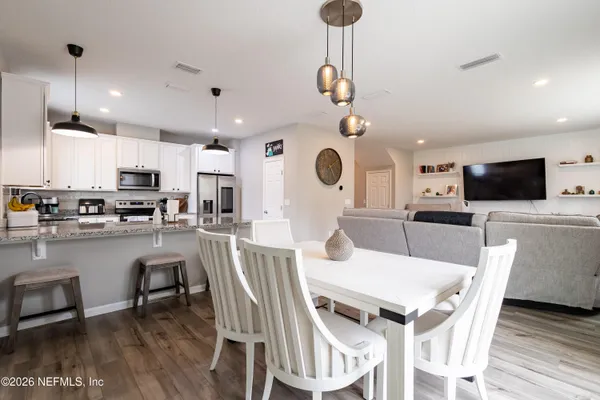 a view of a dining room and livingroom with furniture wooden floor a rug a fireplace