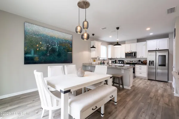 a kitchen with a dining table chairs stainless steel appliances and cabinets