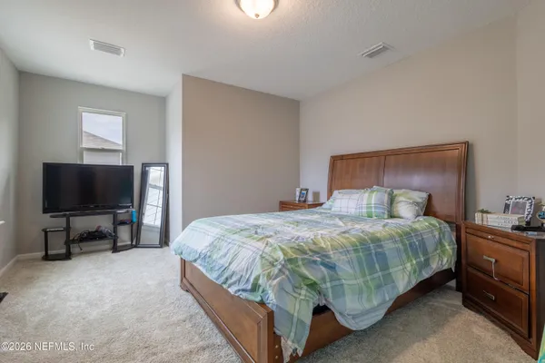 a bedroom with a bed and a flat tv screen on a dresser