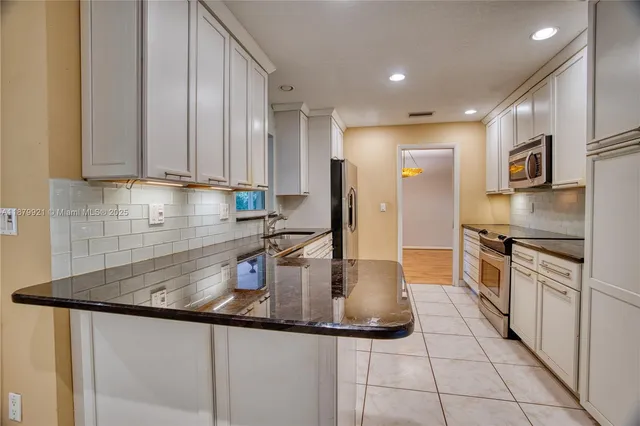 a kitchen with kitchen island granite countertop a sink stainless steel appliances and cabinets