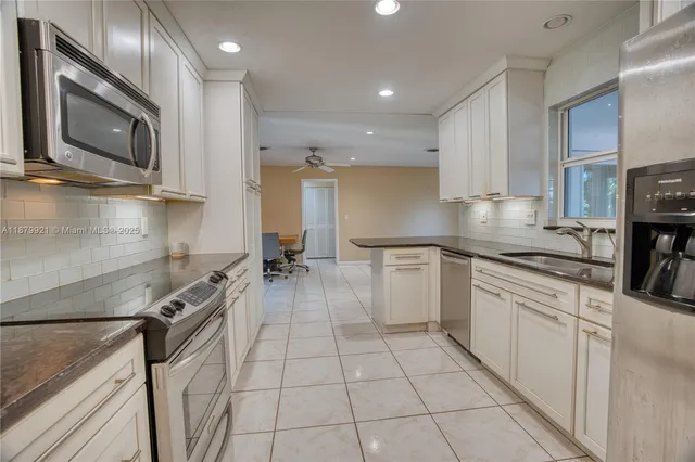 a kitchen with stainless steel appliances a sink a stove top oven a counter space and cabinets