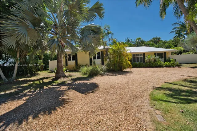 a view of a house with a yard and palm trees