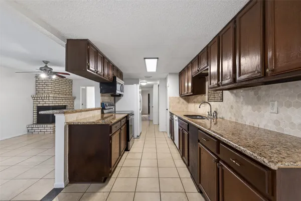 a large kitchen with granite countertop stainless steel appliances and wooden cabinets
