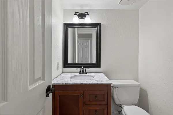 a bathroom with a granite countertop sink a toilet and a mirror