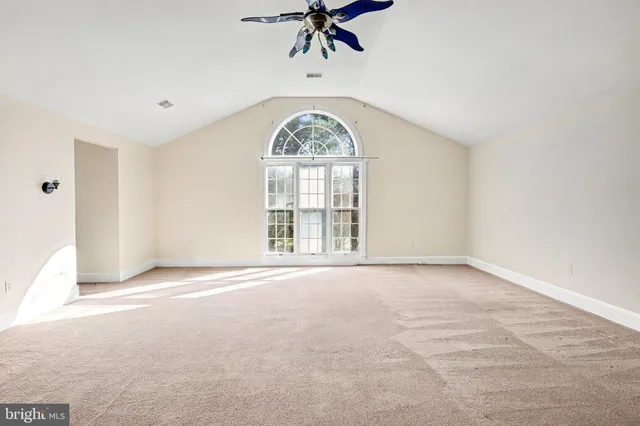 an empty room with a large window and ceiling fan