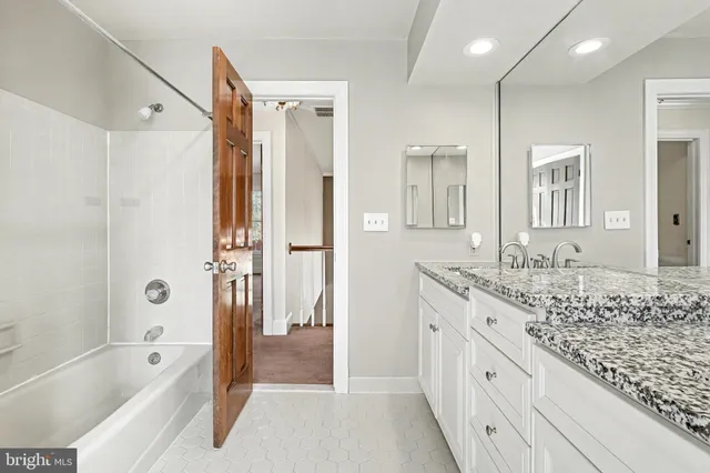 a spacious bathroom with a granite countertop tub sink shower and mirror