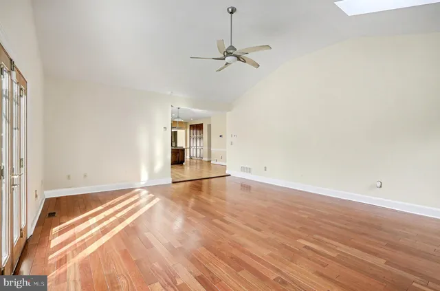 an empty room with wooden floor fan and windows