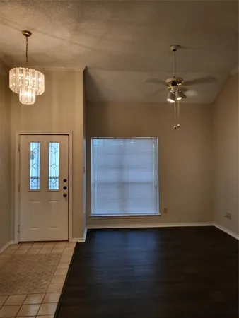 a view of a room with wooden floor chandelier fan and kitchen view