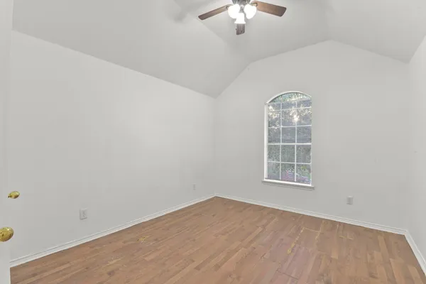 an empty room with wooden floor chandelier and windows