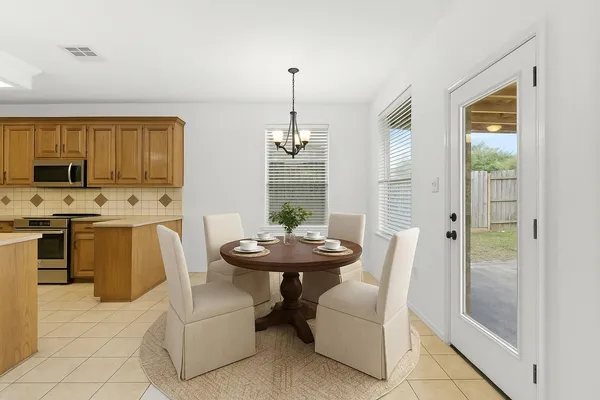 a dining room with furniture a chandelier and kitchen view