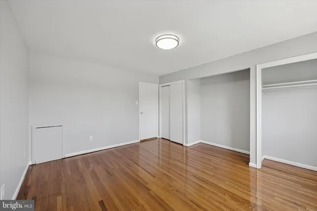 a view of an empty room with wooden floor and closet