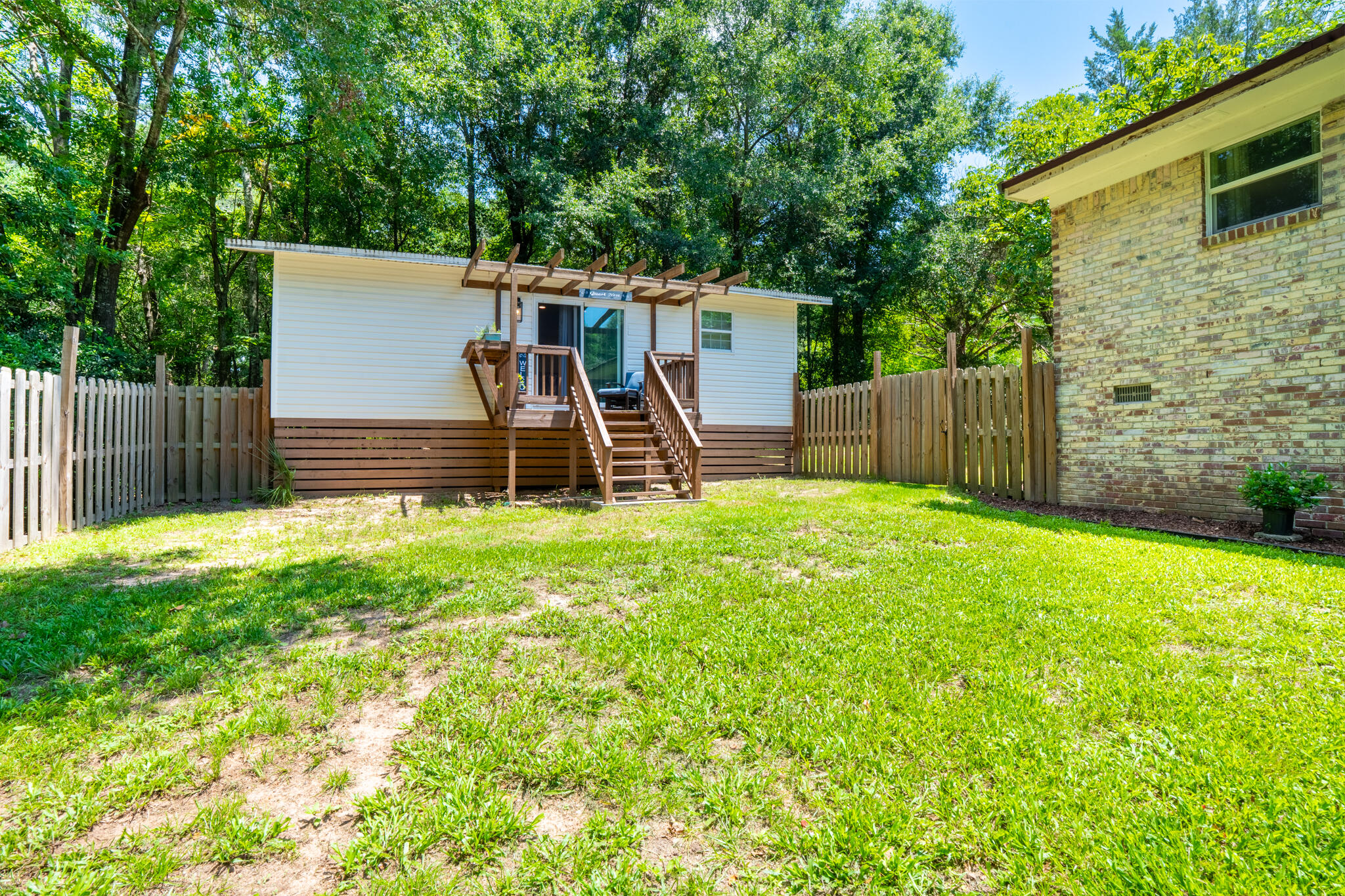 156 Lindberg Street Crestview, FL 32536 - Photo 16 of 25 a view of a backyard with a small cabin and wooden fence