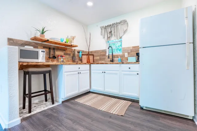 a kitchen with a sink a refrigerator and wooden floor