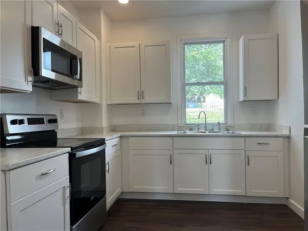 a kitchen with stainless steel appliances granite countertop a sink a stove a microwave and wooden cabinets