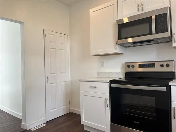 a kitchen with stainless steel appliances white cabinets and a stove top oven