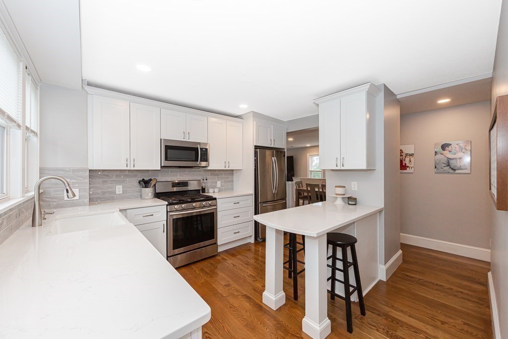 26 Foss Street, Unit 1 Medford, MA 02155 - Photo 7 of 35 a kitchen with granite countertop a stove top oven a sink dishwasher a refrigerator and white cabinets with wooden floor