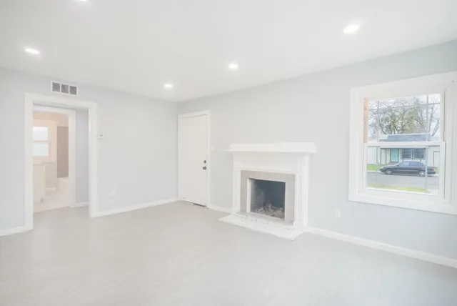 an empty room with windows and fireplace