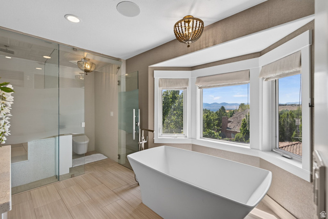 12308 Mariah Circle Draper, UT 84020 - Photo 70 of 293 Contemporary bathroom featuring a freestanding tub, glass-enclosed shower, light wood-finish flooring, and a bay window with natural scenery
