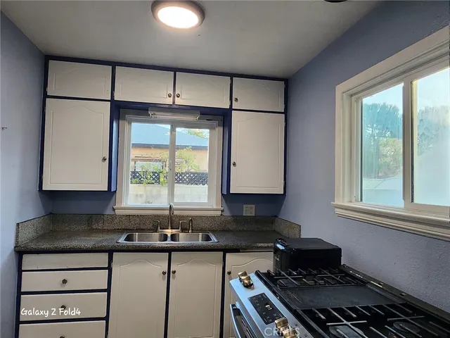 a kitchen with granite countertop a sink a stove and a window