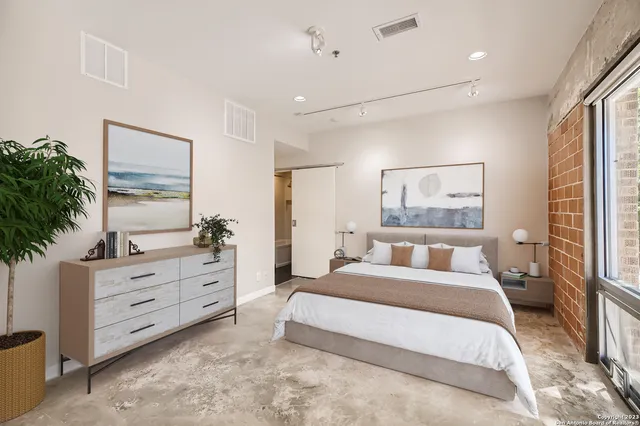 a spacious bedroom with a large bed and a potted plant on the dresser