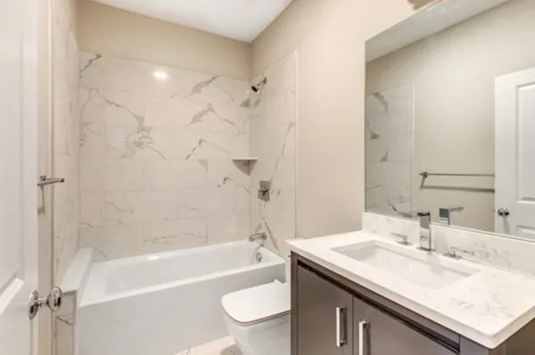 a bathroom with a granite countertop sink a toilet and bathtub