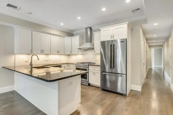 a kitchen with kitchen island a counter top space a refrigerator and a sink
