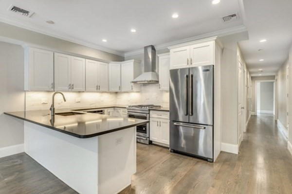 205 West 8th Street, Unit 4 Boston, MA 02127 - Photo 5 of 22 a kitchen with kitchen island a counter top space a refrigerator and a sink