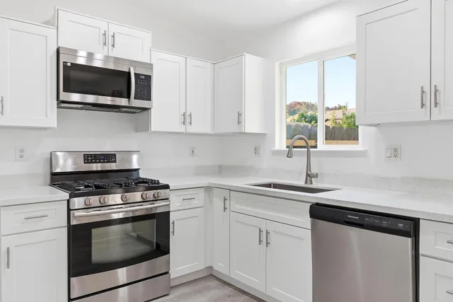 a kitchen with cabinets stainless steel appliances a sink a stove and a window