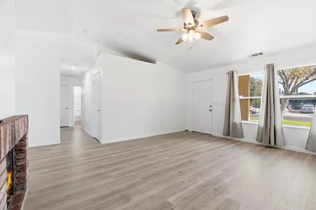 a view of an empty room with window and wooden floor