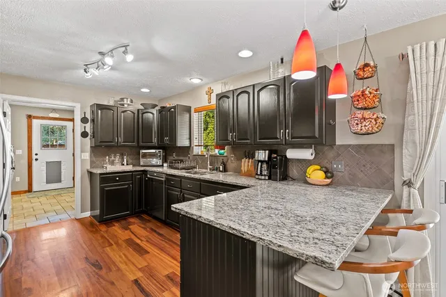 a kitchen with stainless steel appliances granite countertop a sink dishwasher and a stove with wooden cabinets