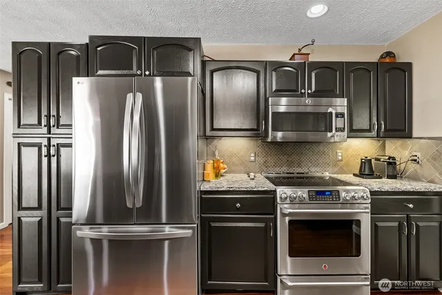 a kitchen with stainless steel appliances granite countertop a refrigerator a stove and a sink