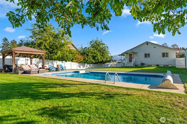 a view of swimming pool with lawn chairs under an umbrella