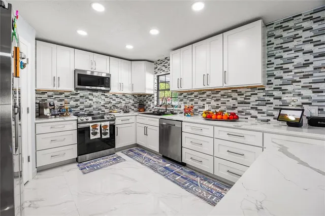 a kitchen with granite countertop white cabinets and stainless steel appliances