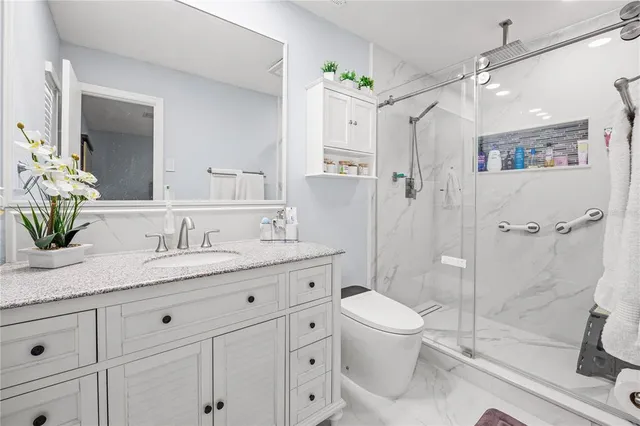 a bathroom with a granite countertop sink a toilet and shower